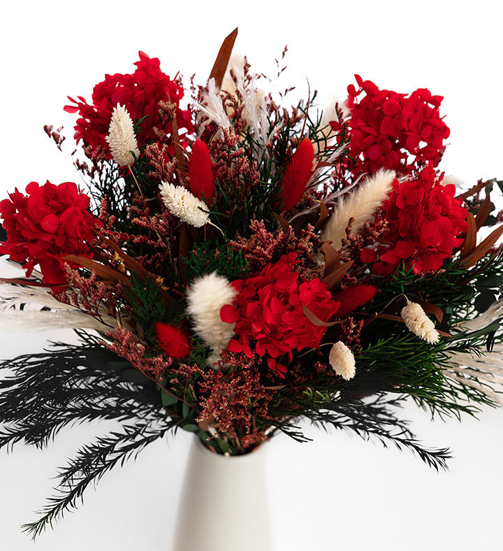 Close-up of red hydrangea, white bunny tails and feathery green foliage in the Jolly Holiday bouquet